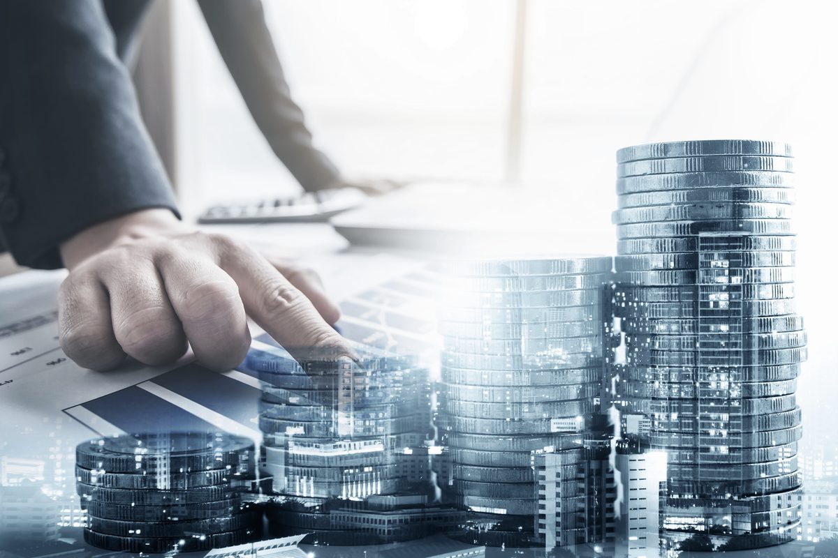 Analyse d’un plan de financement immobilier au bureau, piles de pièces et silhouette de ville